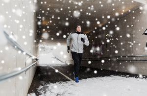 Man running in winter in the snow outside its cold he's doing a workout 