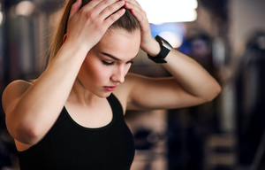 anxiety fitness woman in gym feeling worried hands up on head 